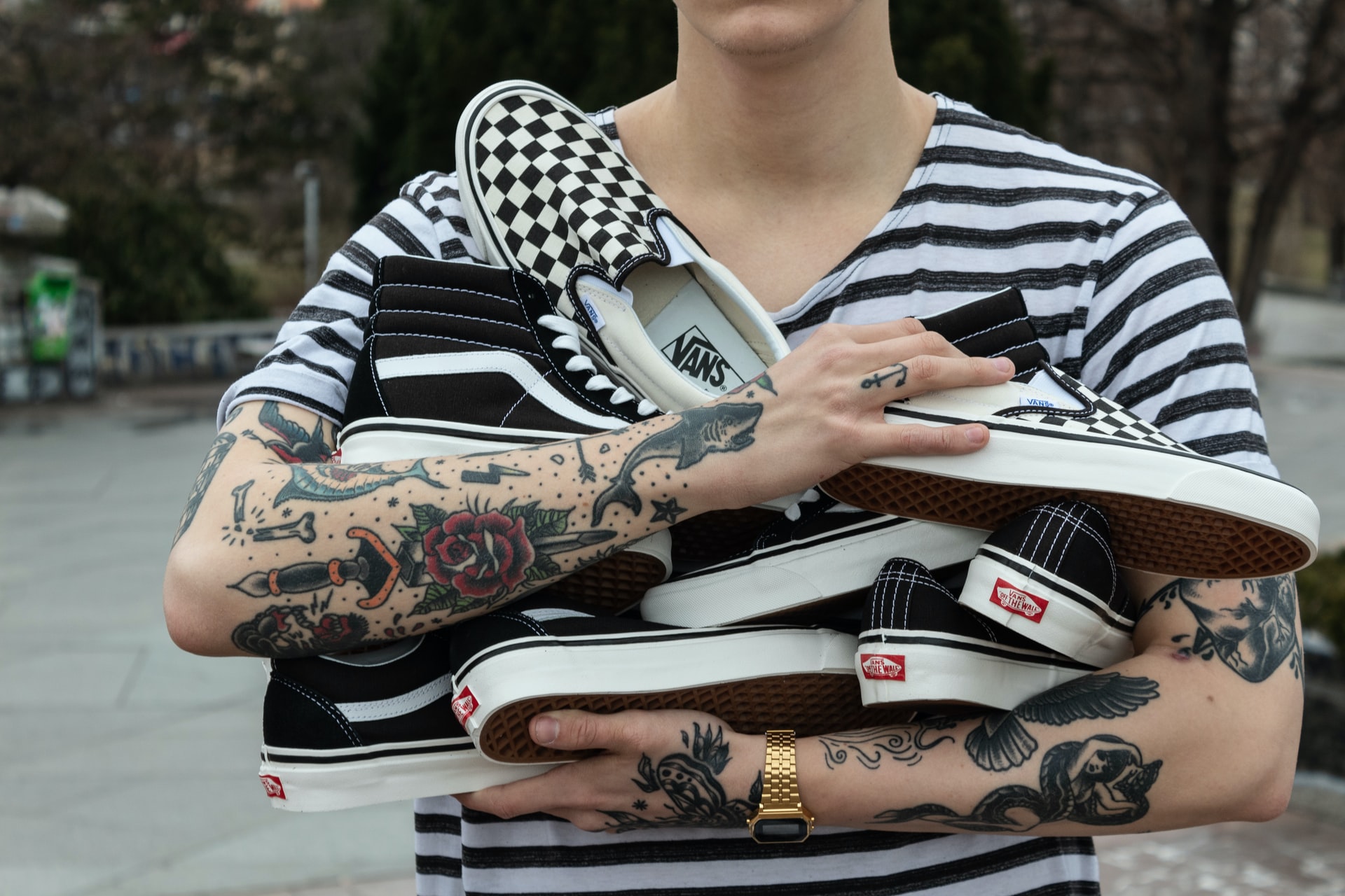 a tattooed social media influencer cradling a bunch of vans shoes