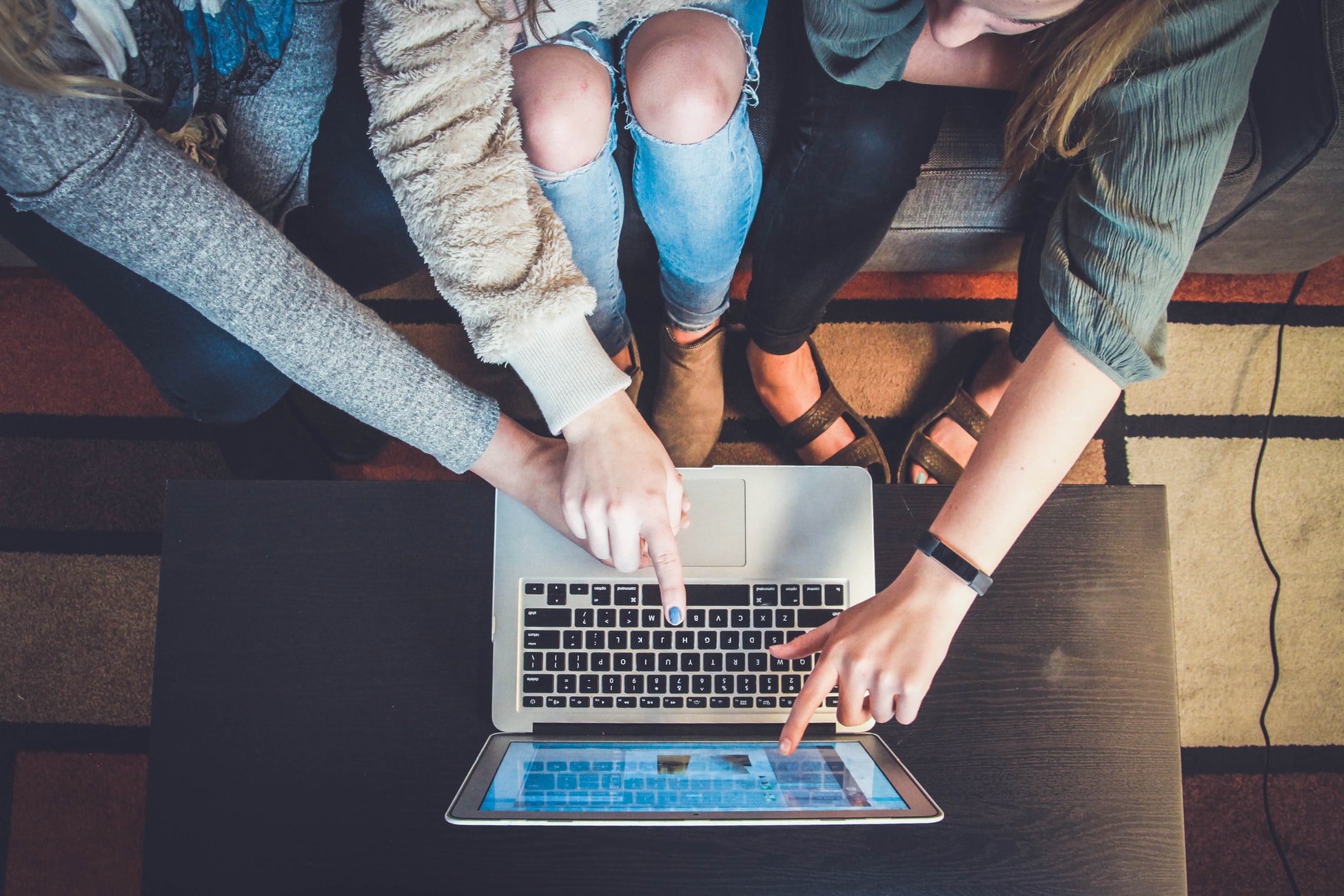 Three marketing professionals analyzing a website shown through a MacBook screen.