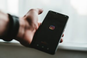 person holding black android smartphone with instagram boot screen loading up