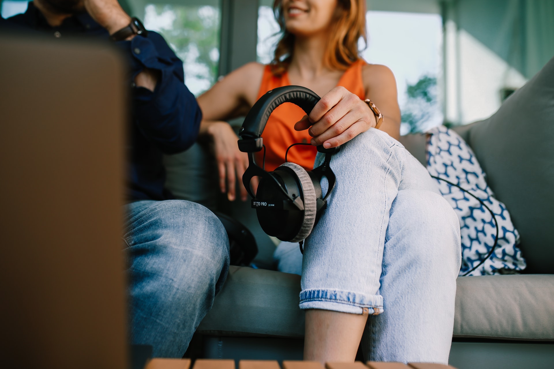a woman in an orange shirt holding headphones while recording a podcast in a podcast session