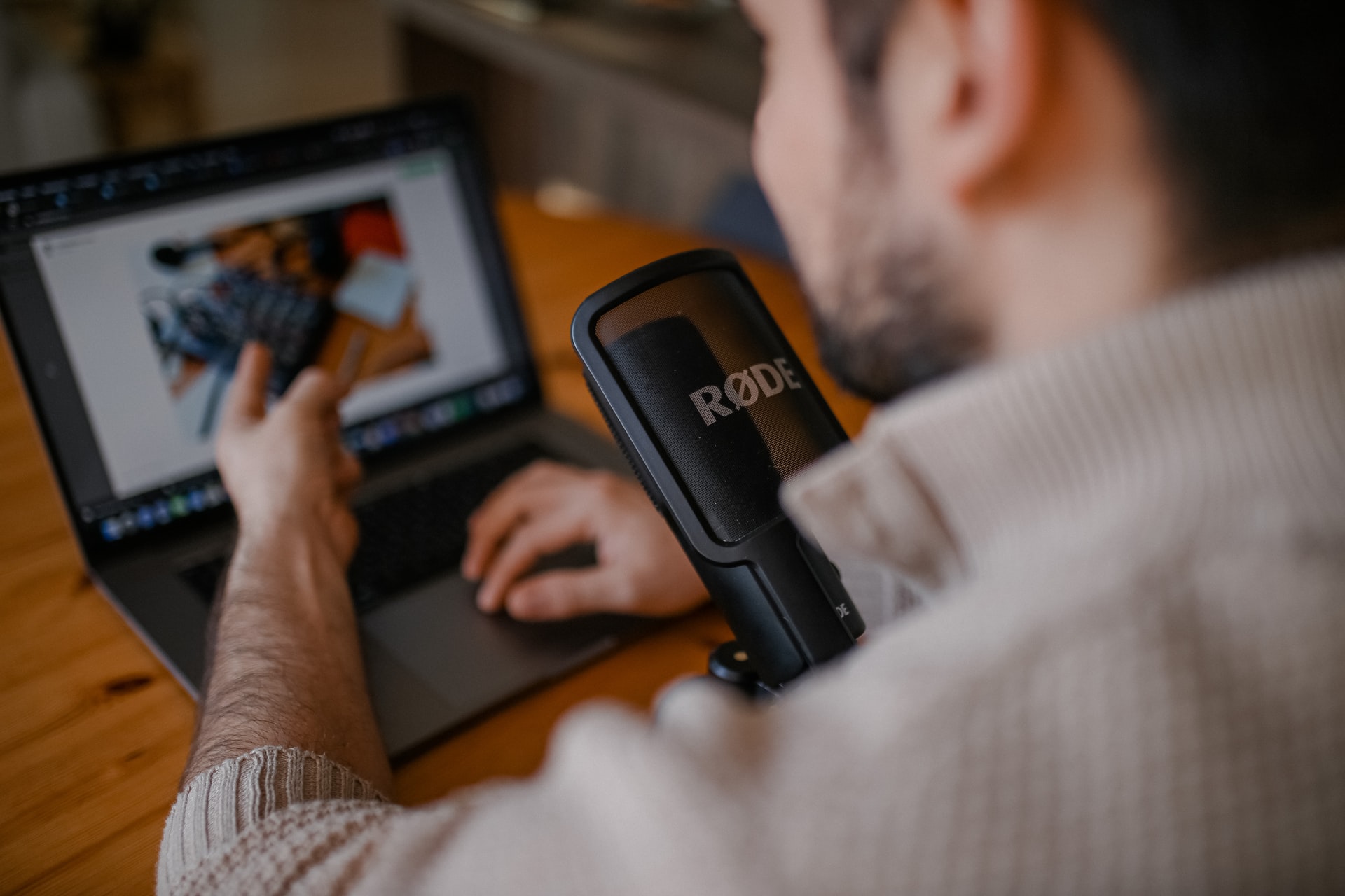a social media content creator showing a project on the screen with a microphone at work while podcasting