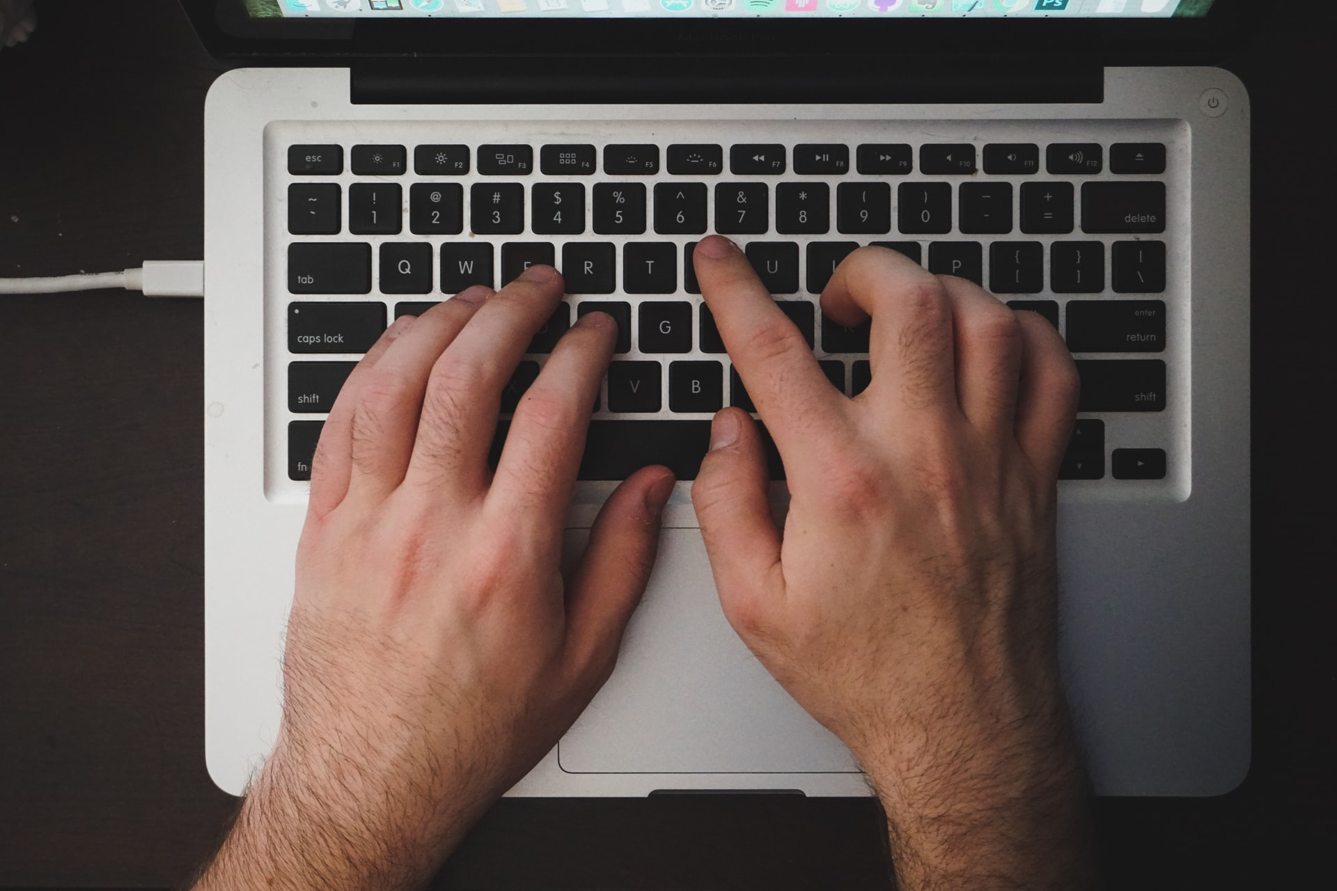 man typing on a macbook pro