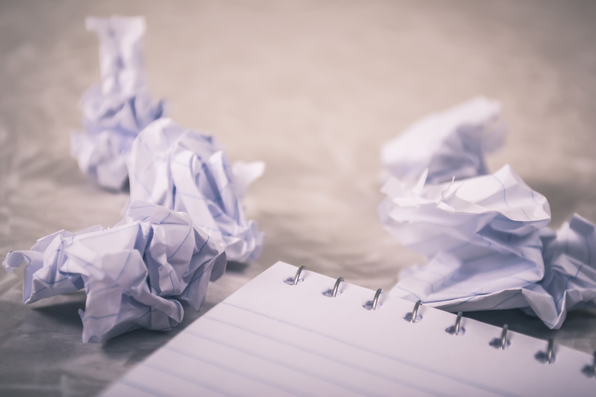 pieces of crumpled paper next to a writing pad