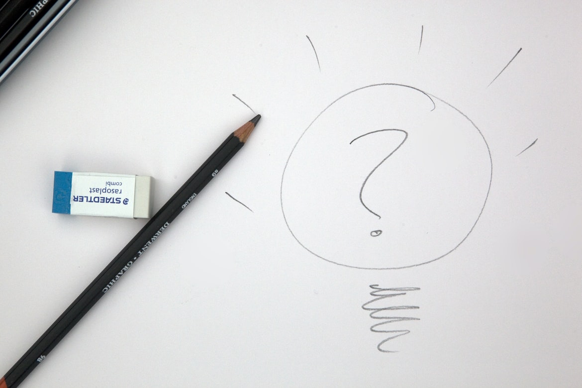 question mark and bulb scribbled onto a piece of paper next to an eraser and pencil