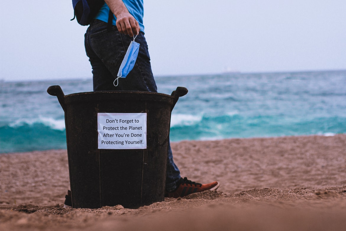 man throwing his facemask in a garbage can