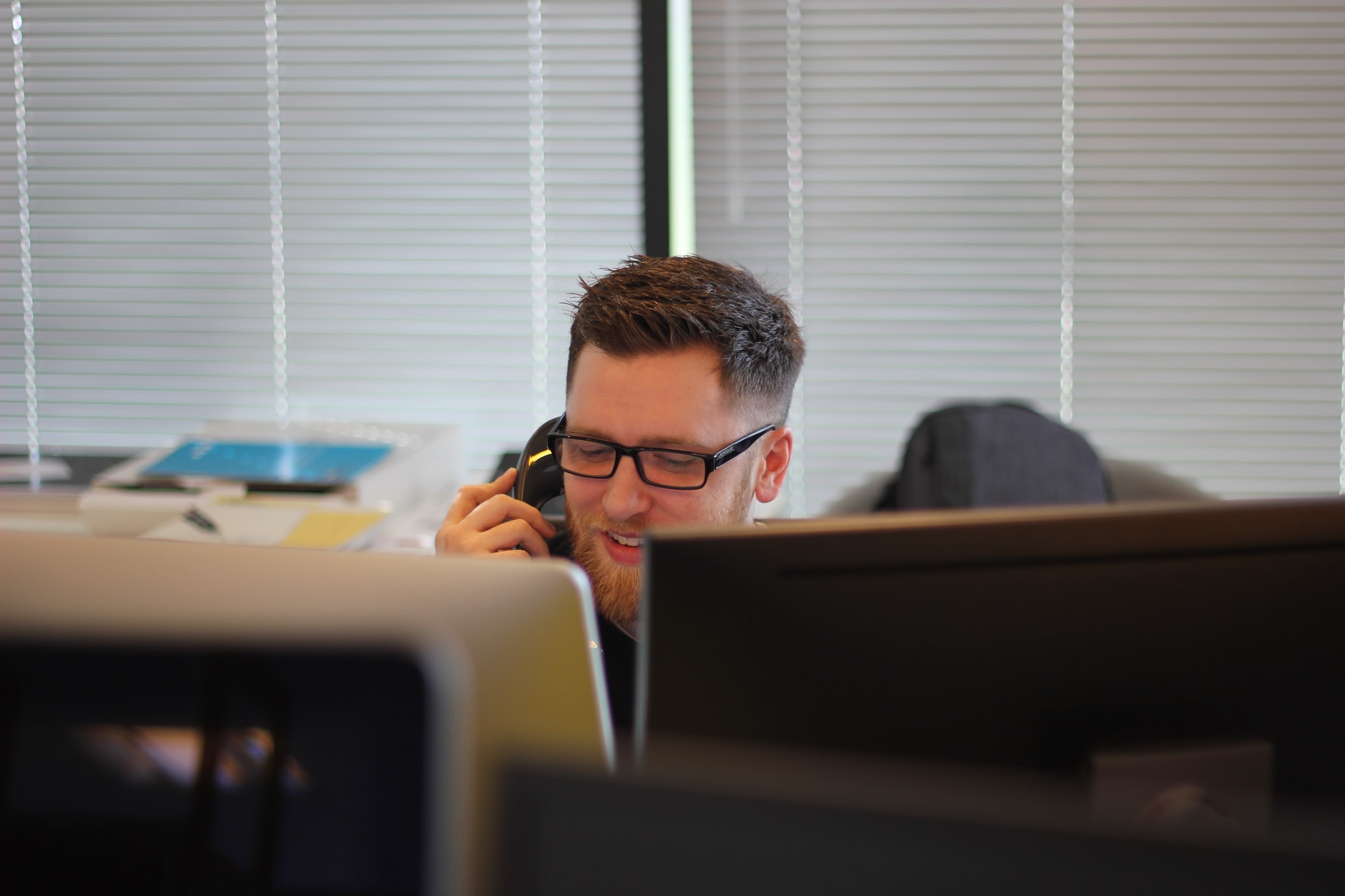 man using phone inside his work cubicle