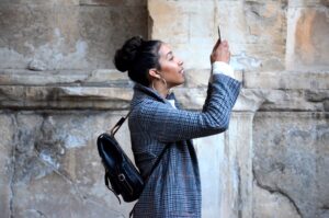 woman in blue plaid coat holding up her phone