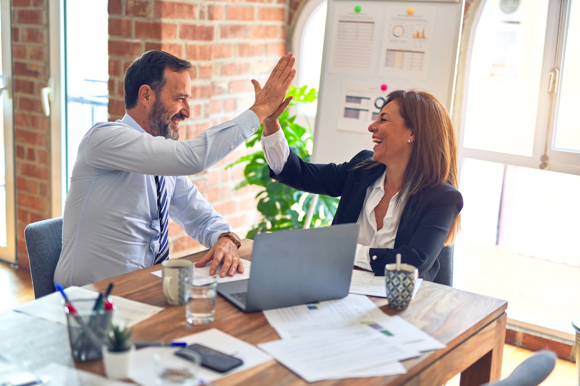 a man and woman high-fiving at their work station