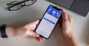 a man holding a phone with the Facebook app on