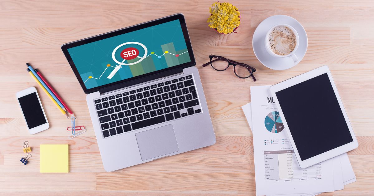 a macbook, iPad, and iPhone on a desk with the SEO logo on the laptop screen